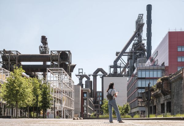 Personne se déplaçant sur le site industriel de Belval avec anciens hauts fourneaux et structures métalliques